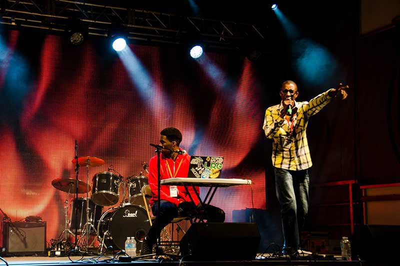 An image of Orijin performing with a drummer behind him.